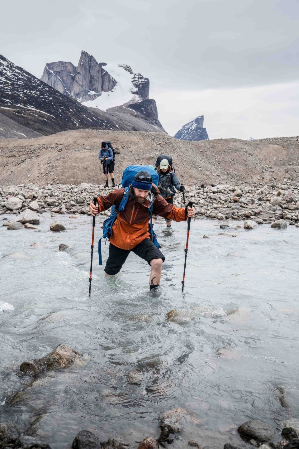 Towering rock faces rising sharply above the valley, as hikers traverse the rugged trail below.