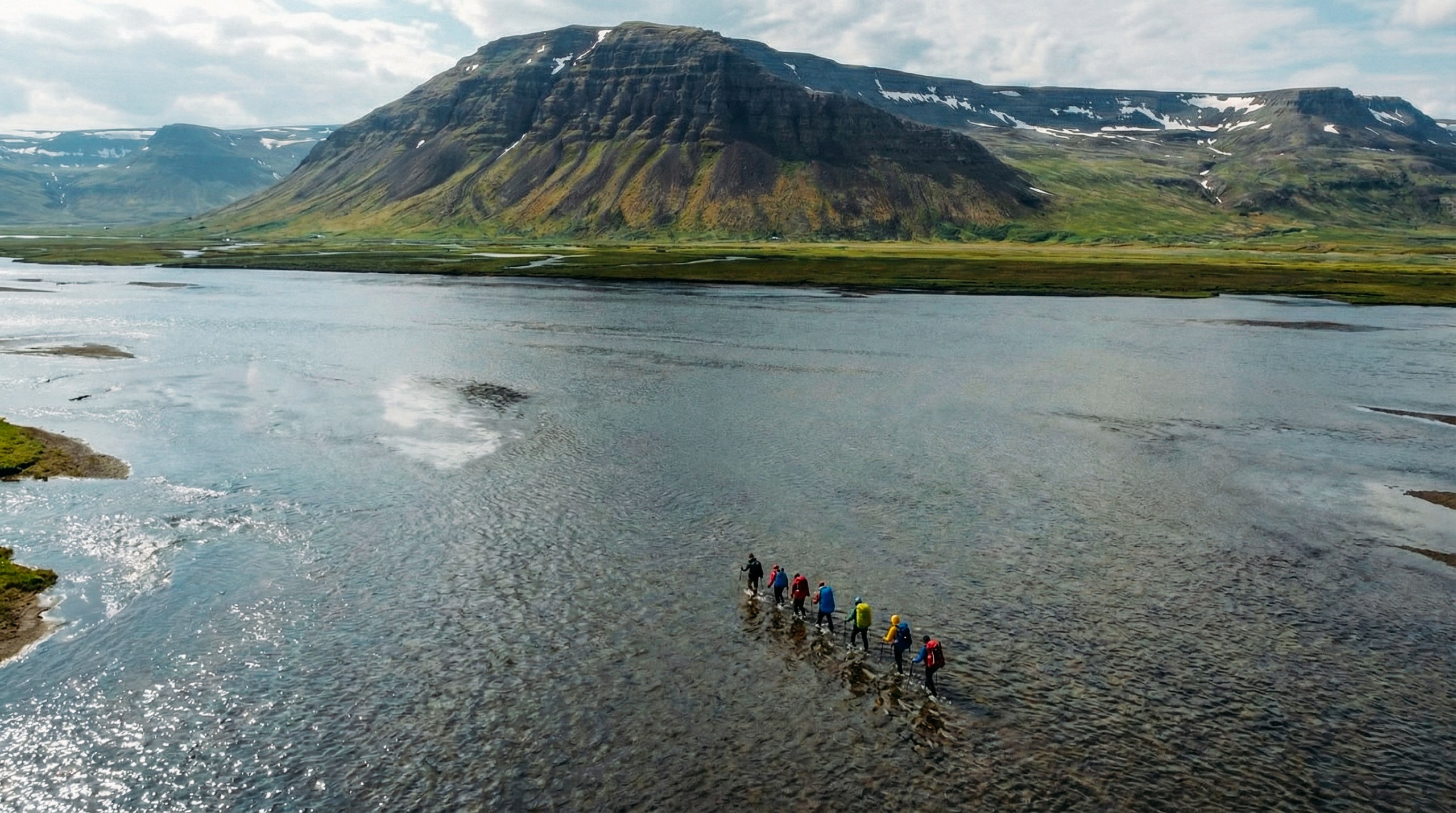 Group of hikers crossing a river in the Hornstrandir Nature Reserve