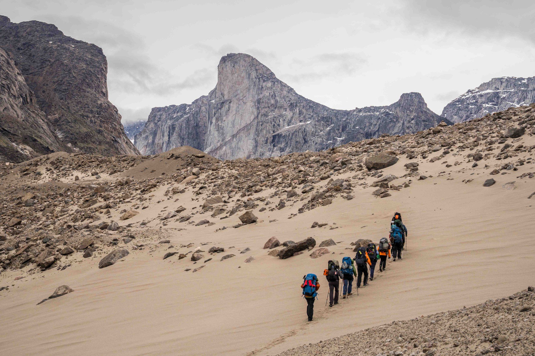 Akshayuk Pass Trail - Views of the sheer rock face of Mt. Thor, boasting the world’s tallest vertical drop, looming over the rugged terrain of Baffin Island.