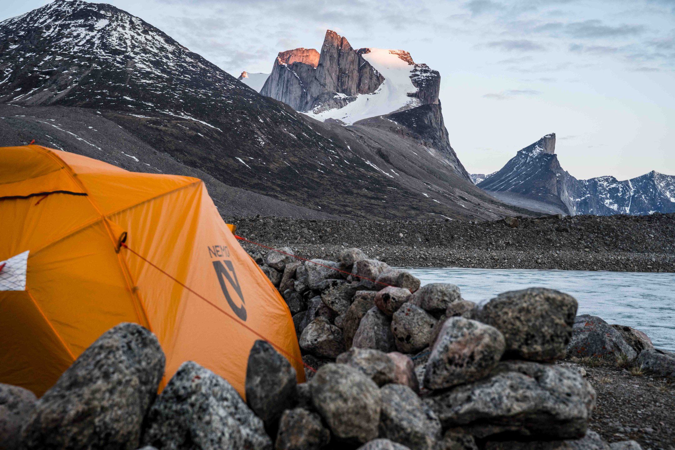 Tent secured by boulders against Arctic winds with Mount Thor in the background.