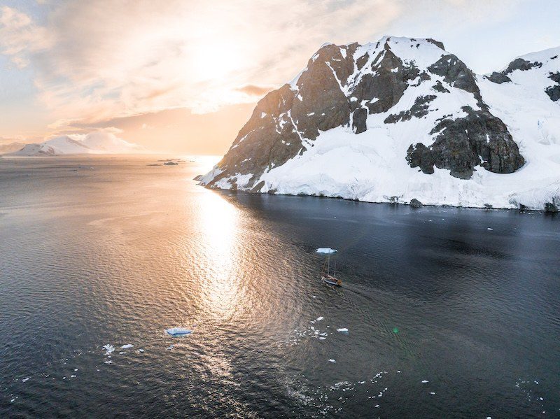 Aerial view of the expedition vessel Ocean Tramp navigating the rugged yet stunning shores of Antarctica.
