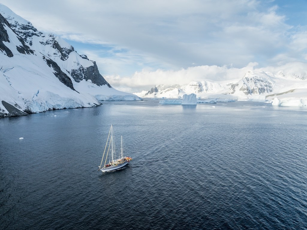 Aerial view of Ocean Tramp expedition yacht navigating icy waters in Antarctica