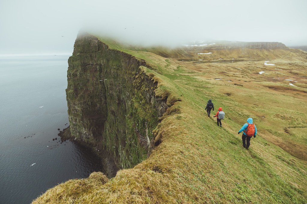 Group of hikers walking along misty ridge in Hornstrandir Nature Reserve Iceland