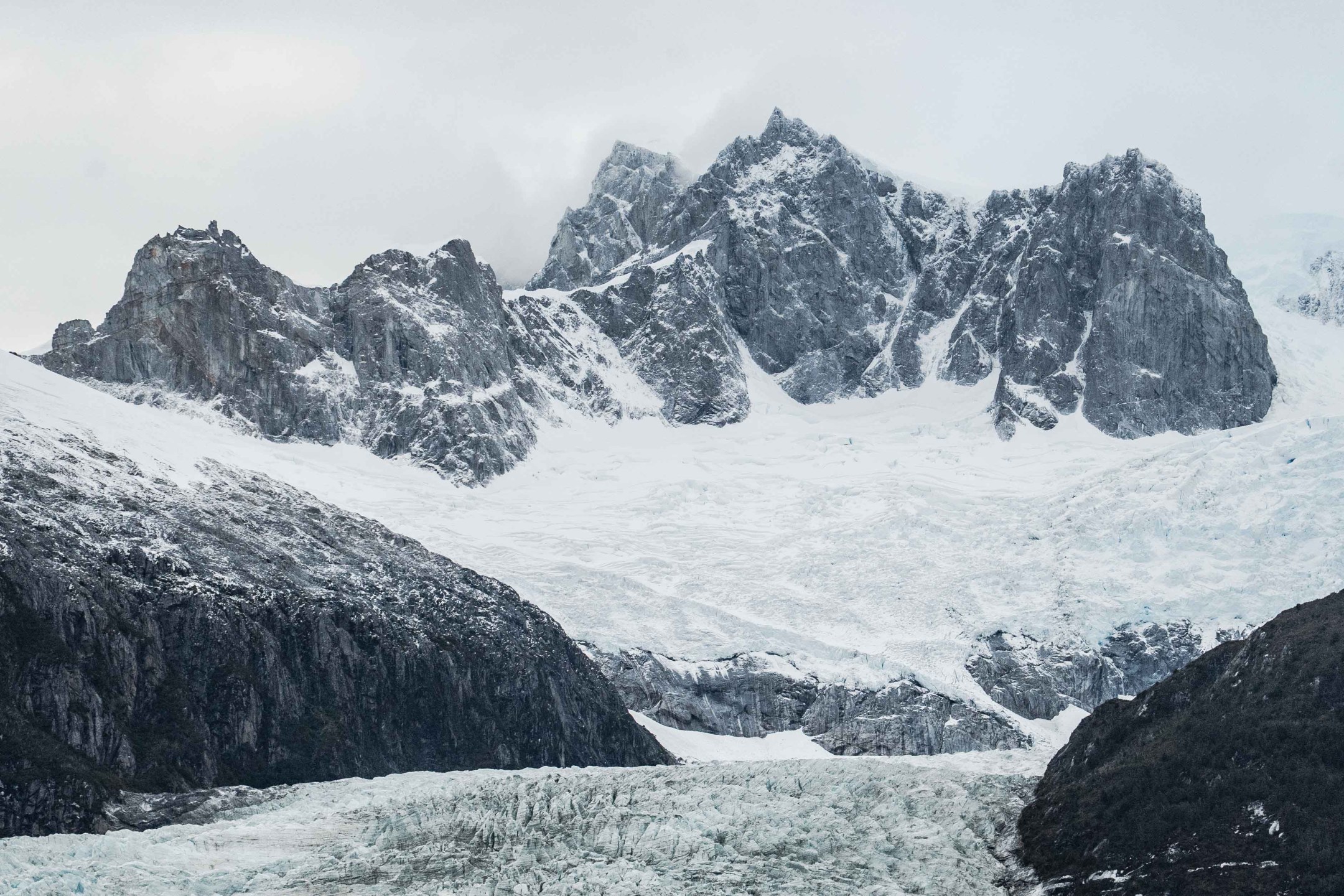 Hiking Patagonia - The sailboat securely anchored in the remote fjords of Patagonia, reflecting on the calm, glacial waters.