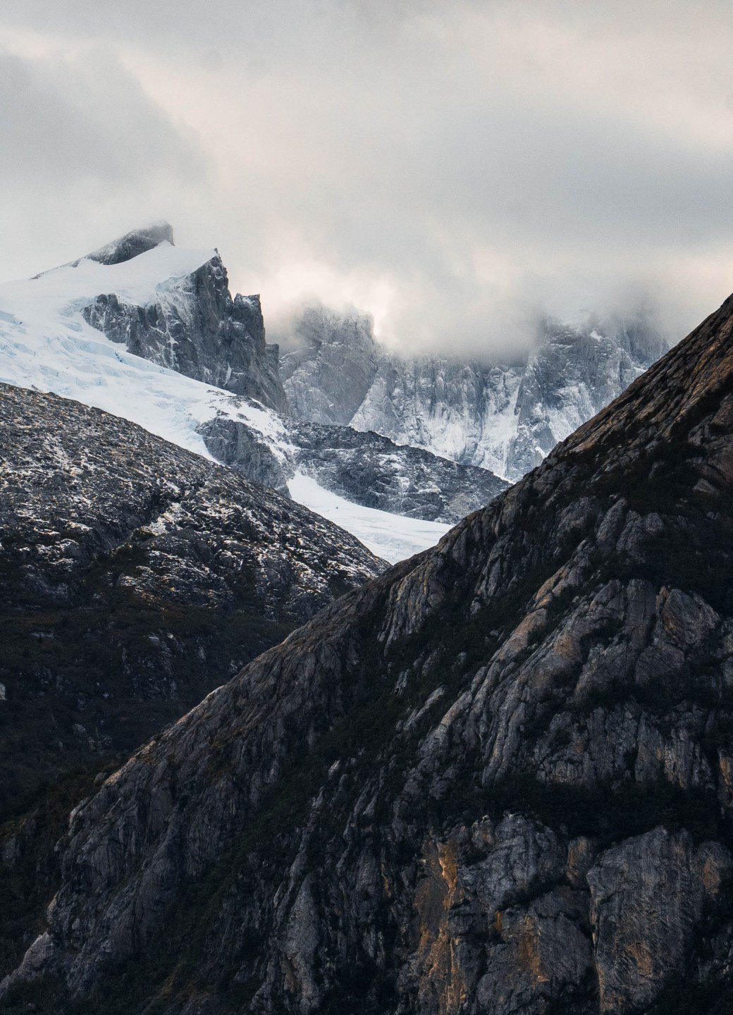Hiking Patagonia - Lush, untouched Patagonian forest stretching to the water’s edge, with a massive glacier cascading down the mountains in the background.