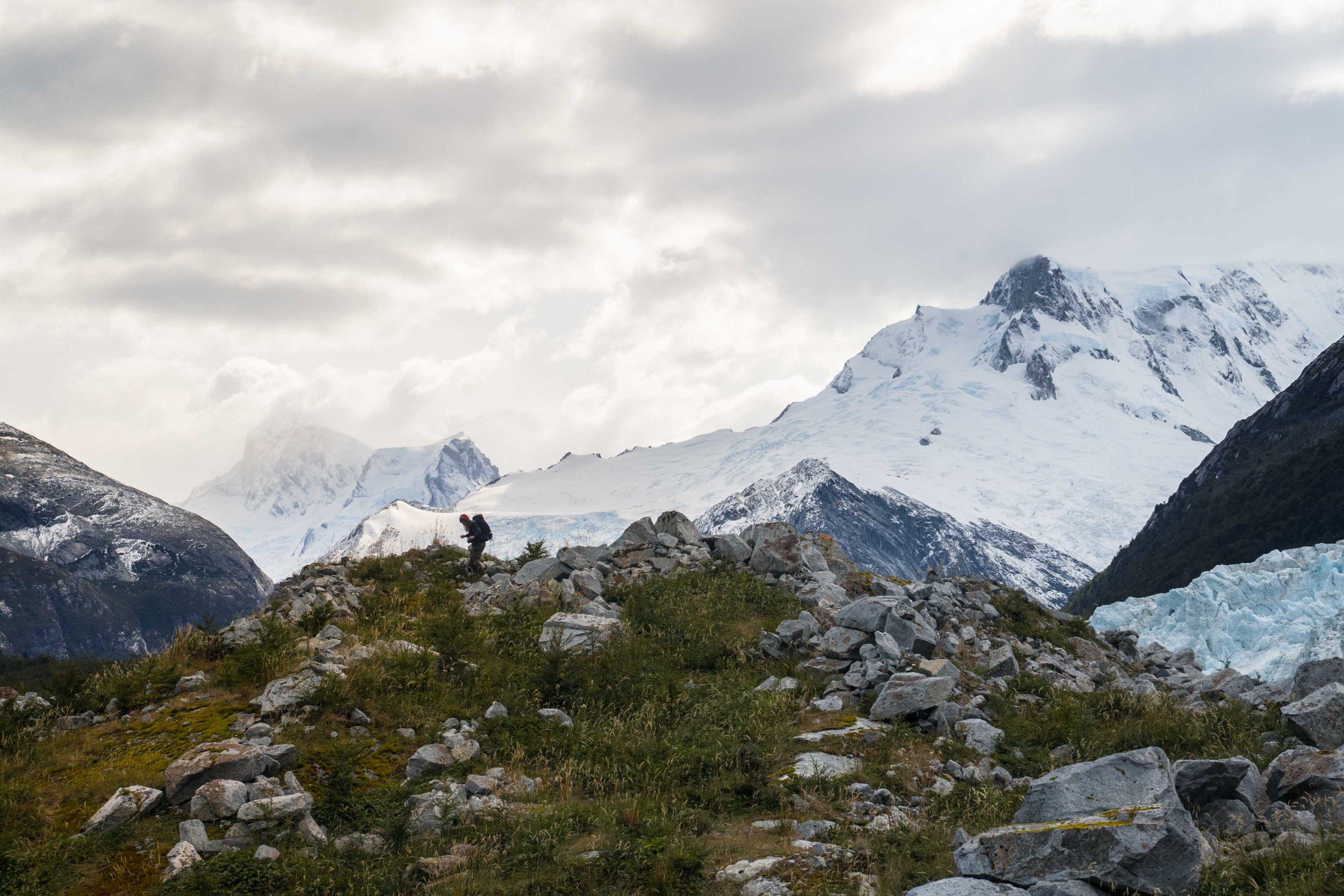 Hiking Patagonia - A hiker coming down a hill with the glaciers on the back.
