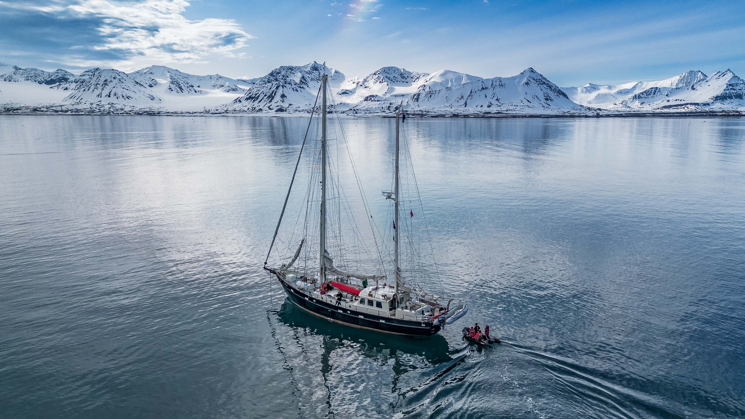 Expedition sailboat navigating calm Arctic waters under clear skies in Svalbard